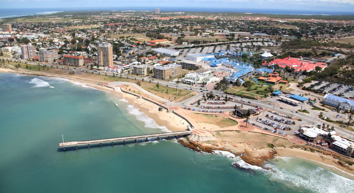 Aerial view of a coastal city with a pier, beach, buildings and ocean.